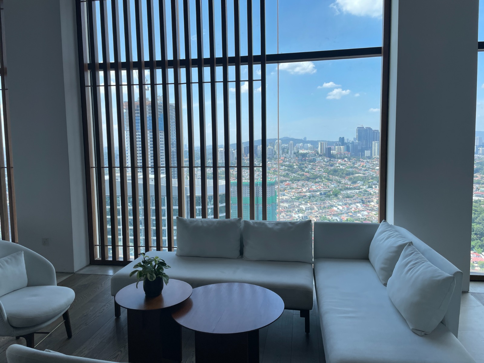 Lounge with white sofas and a city view through tall windows
